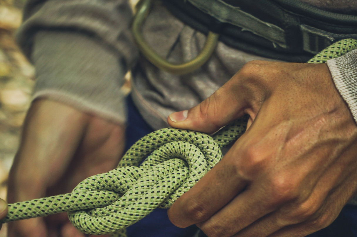 A climber's hands secure a safety knot